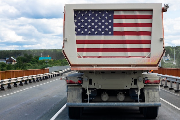 Gros camion avec le drapeau national des Etats-Unis se déplaçant sur l'autoroute,