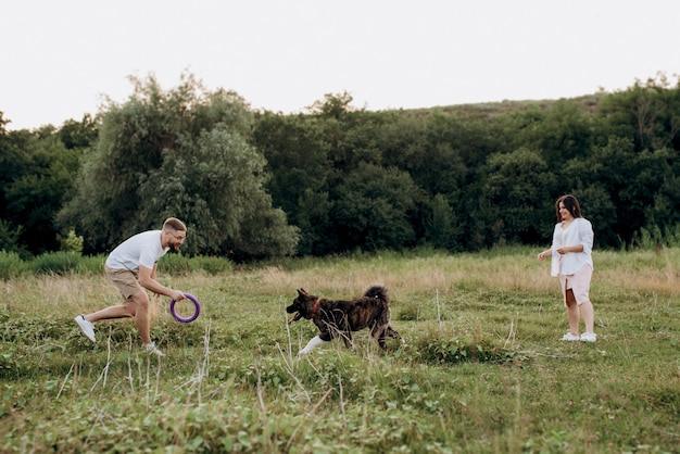 Gros chien pour une promenade avec un gars et une fille dans la prairie verte