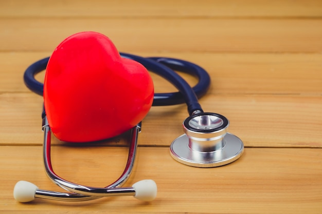 Gros coeur rouge et steythoscope sur une vieille table en bois