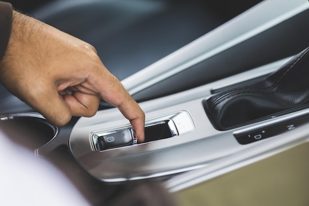 Gros doigt mâle poussez le frein de stationnement électrique. Conduire une voiture de luxe.