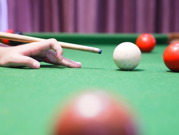 Gros fille à la main sur la table verte, jouant des boules de billard.