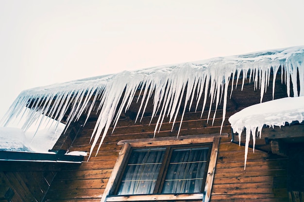 Gros glaçons sur le toit d'une maison en bois