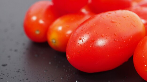 Gros groupe de tomates cerises sur fond noir.