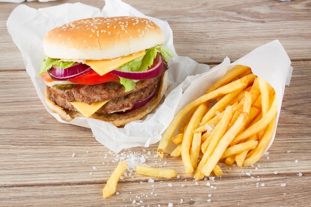 Gros hamburger frais avec frites sur table en bois