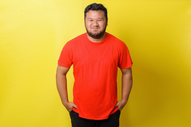 Un gros homme asiatique en t-shirt rouge est en train de sourire isolé sur fond jaune