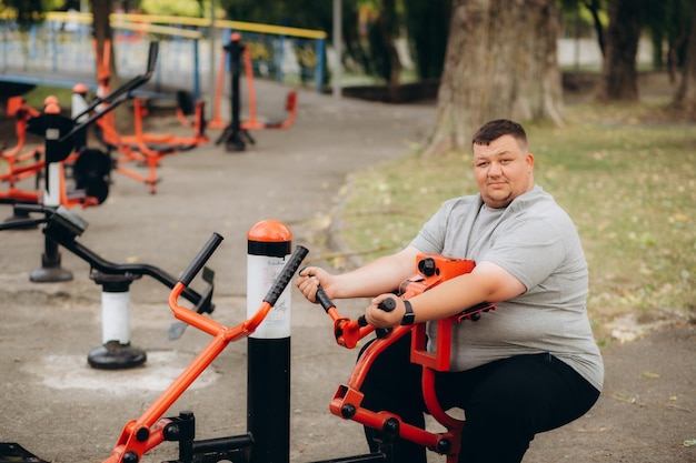 un gros homme fait du sport dans le parc