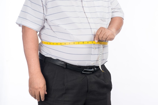 Gros homme mûr mesurant son ventre avec un ruban de mesure, isolé sur fond blanc