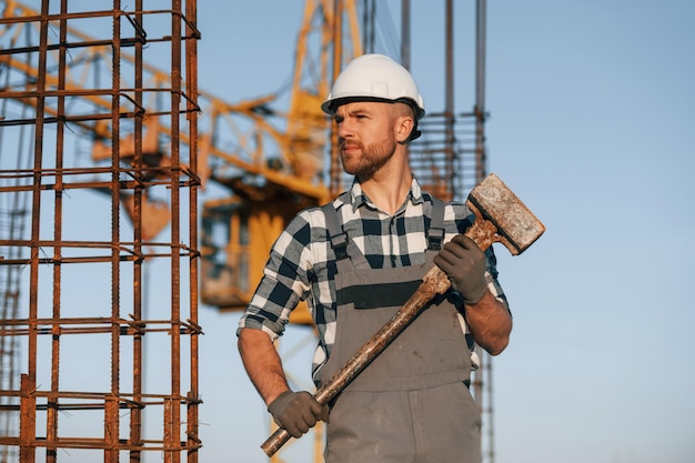 Photo avec un gros marteau dans les mains, l'homme travaille sur le chantier pendant la journée