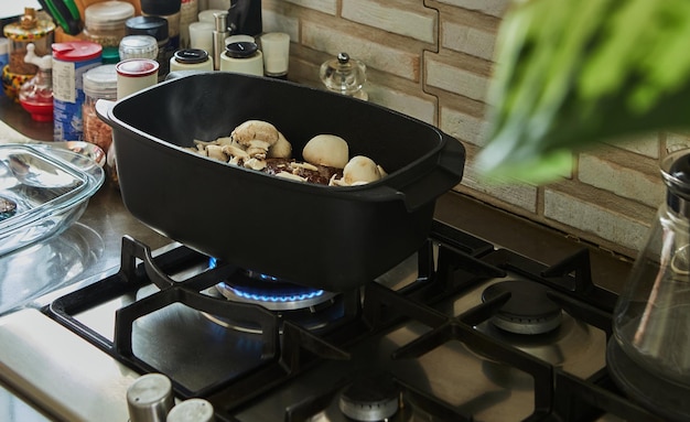 Un gros morceau de bœuf aux champignons est frit dans un chaudron spécial sur une cuisinière à gaz