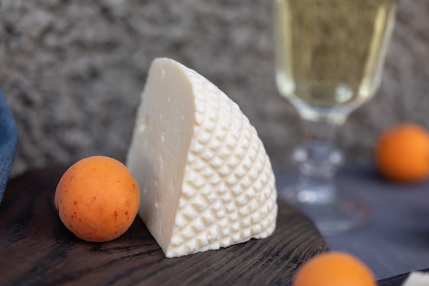 Photo gros morceau de fromage fermier frais et d'abricots sur une planche de cuisine vintage