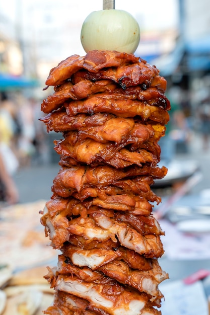 Gros morceaux de viande à la broche au marché alimentaire de rue en Thaïlande, gros plan. Brochettes de viande de poulet grillées à la broche. Fast food.