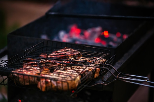 de gros morceaux de viande juteuse sont frits à l'extérieur sur le gril sur des charbons ardents