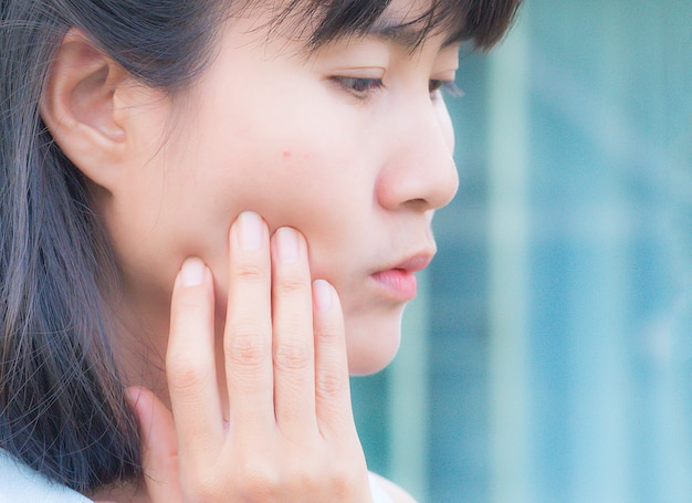 Gros plan de l'acné peu sur le visage femme asiatique sur l'image floue de fond bleu