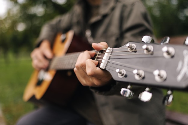 Gros plan d'un adolescent jouant de la guitare doigt masculin sur des cordes faisant de l'ambiance d'automne d'accords à l'extérieur