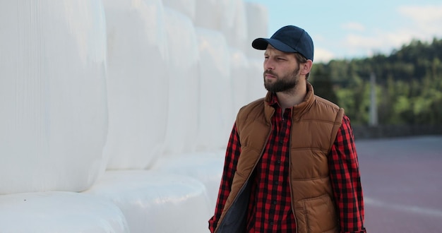 Gros plan d'un agronome professionnel marchant sur une pile de foin dans la campagne saisonnière Le propriétaire de l'agro-industrie vérifie la pile de balles sur les terres agricoles d'automne