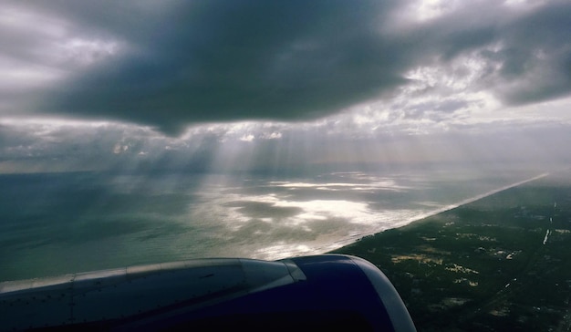 Un gros plan de l'aile d'un avion au-dessus d'un paysage nuageux