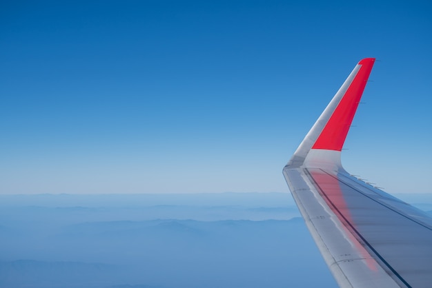 Gros plan de l'aile d'avion avec ciel bleu et vue paysage nature montagne.