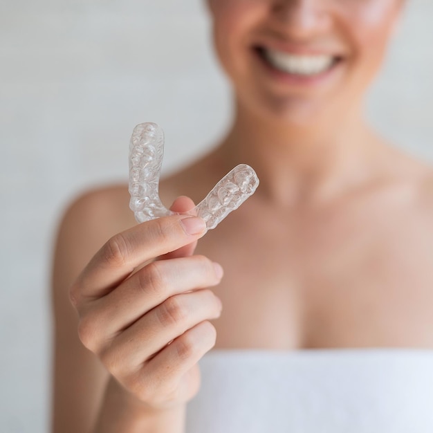 Gros plan d'un aligneur de dents transparent en silicone orthodontique dans les mains des femmes