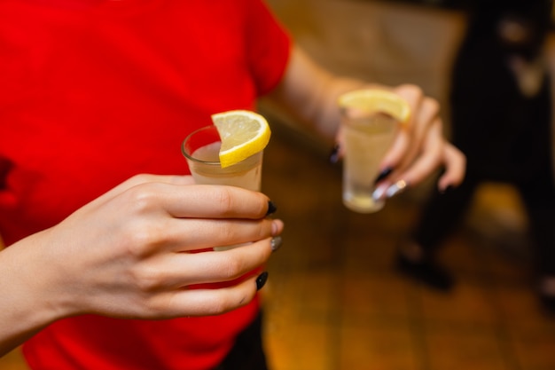 Gros plan d'amies portant un toast avec des verres de cocktails lors d'une fête au bar.