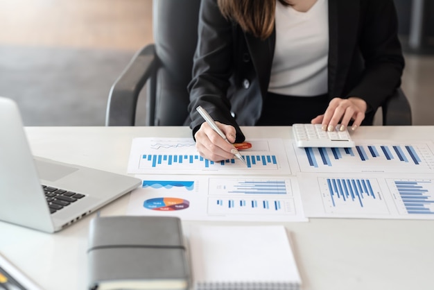 Gros plan d'analyse de travail de femme d'affaires pointant le graphique au bureau.