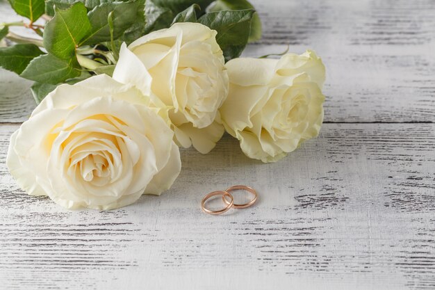 Gros plan des anneaux de mariage sur fond de roses