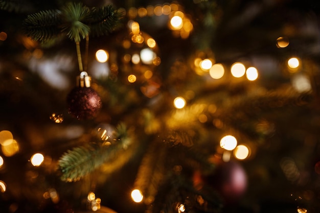 Gros plan de l'arbre de Noël joliment décoré Lumières joyeuses de guirlandes sur un arbre de Noël dans une pièce sombre