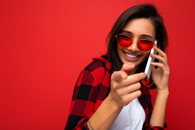 Gros plan assez heureux rire jeune femme brune portant une chemise rouge élégante t-shirt blanc