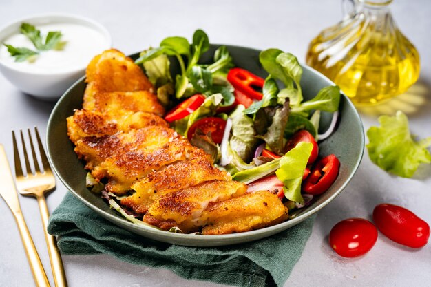 Gros plan d'une assiette avec une délicieuse morue panée avec une salade saine