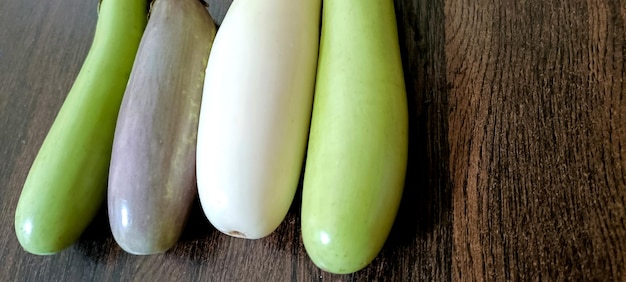 Gros plan d'aubergines fraîches blanches et vertes biologiques ou de brinjal isolés sur fond de bois