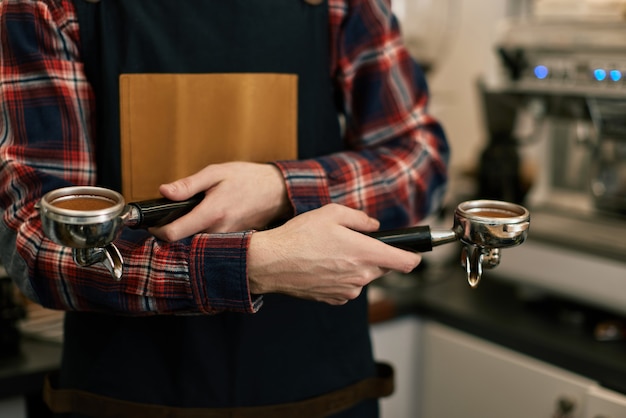 Gros plan, barista en tablier de mouture de café au café