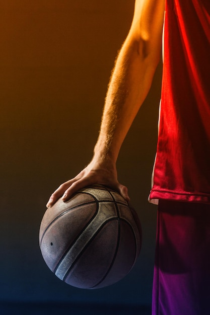 Gros plan sur le basket-ball tenu par un joueur de basket-ball dans une salle de sport