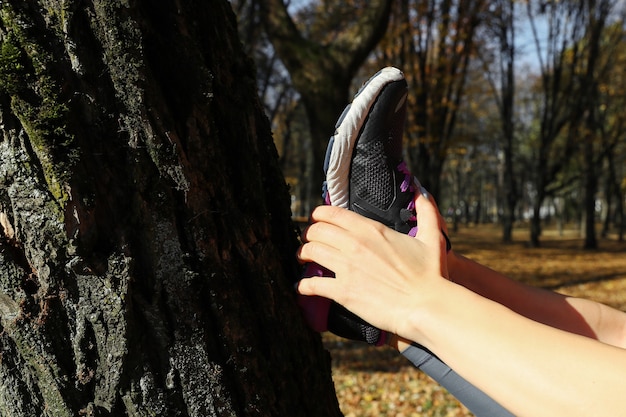 Photo gros plan sur les baskets d'une fille qui s'étire avant de s'entraîner dans le parc