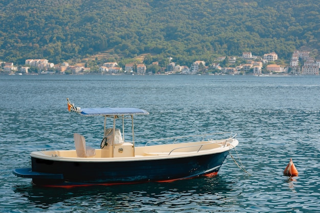 Gros plan d'un bateau à moteur de pêche sur eau calme près de la rive avec des chalets.