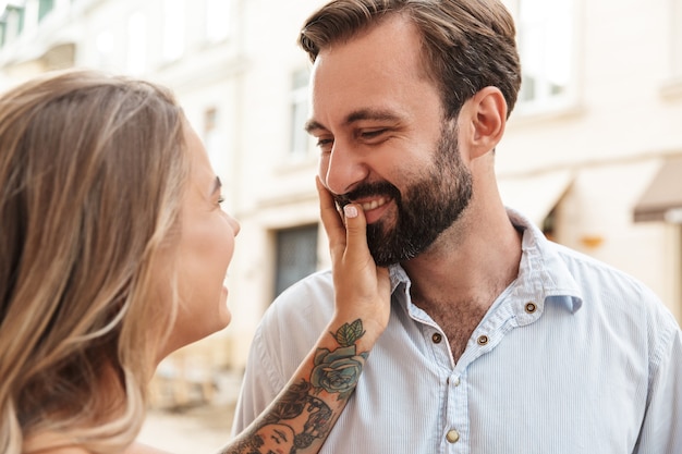 Gros plan d'un beau couple heureux embrassant tout en se tenant dans la rue de la ville, en se regardant