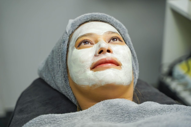 Gros plan beauté femme avec crème de masque blanc sur son visage dans une clinique de beauté