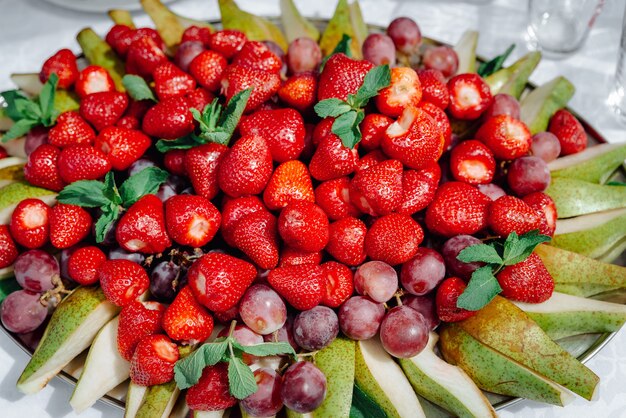 Gros plan sur de beaux fruits tranchés sur le buffet de la table de mariage dans l'assiette en plein air avec des fruits