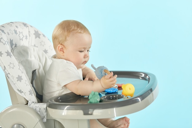 Gros plan d'un bébé assis sur une chaise haute et jouant avec des jouets sur une table