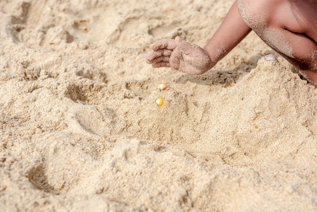 Gros plan bébé enfant jouant avec du sable humide de la côte de la mer touchant le sable image horizontale