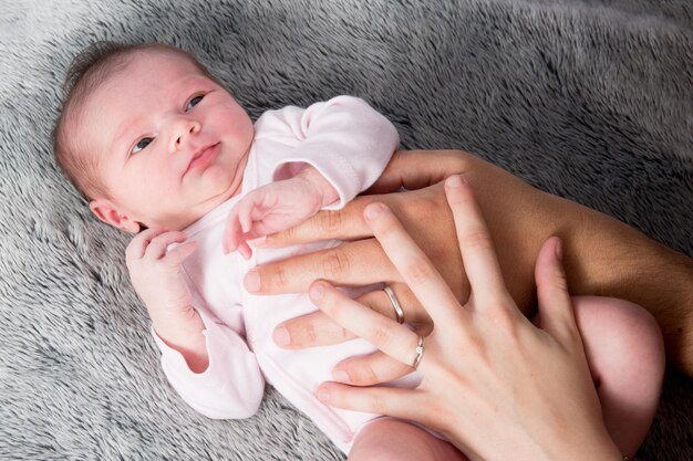 Gros plan sur un bébé nouveau-né avec les mains des parents sur le ventre