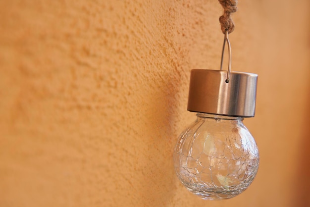 Gros plan d'une belle ampoule LED en cristal accrochée à un mur orange