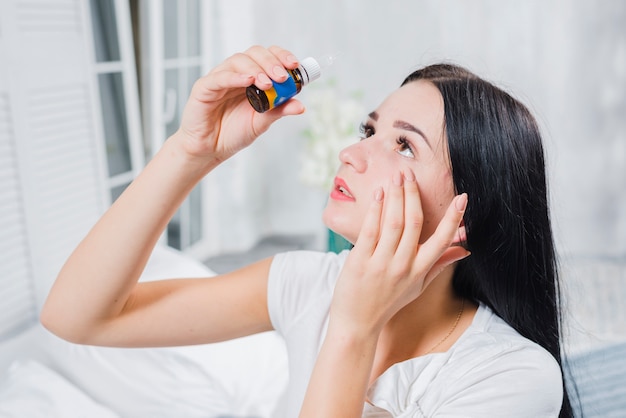 Gros plan d&#39;une belle femme appliquant des gouttes pour les yeux dans ses yeux