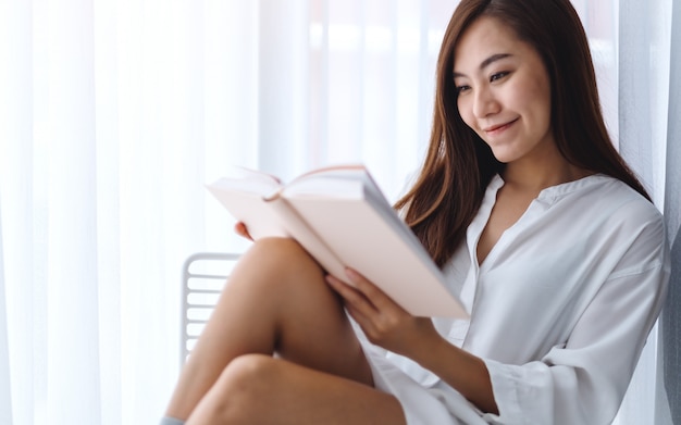 Gros plan d'une belle femme asiatique lecture livre dans une chambre à la maison