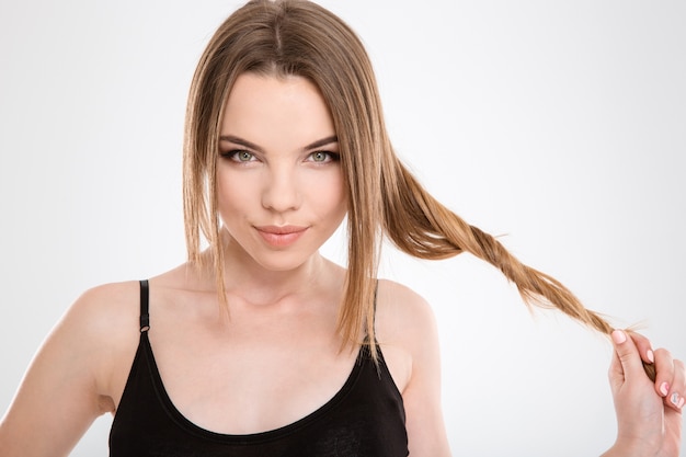 Photo gros plan d'une belle fille tendre sensuelle amusante jouant avec des cheveux sur un mur blanc