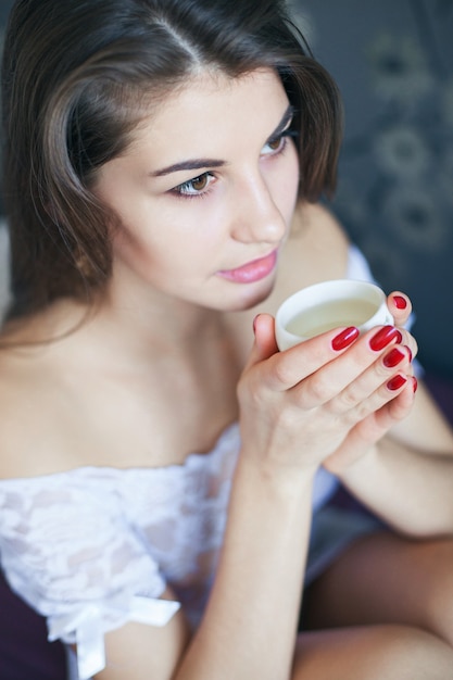 Gros plan sur la belle jeune femme appréciant une tasse de boisson