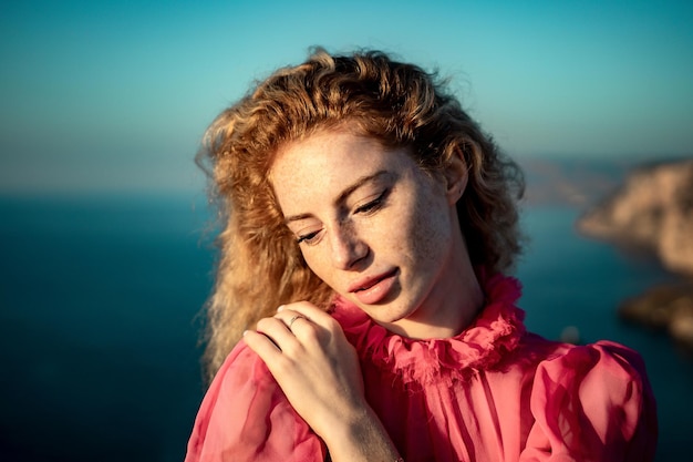 Gros plan d'une belle jeune femme caucasienne aux cheveux blonds bouclés et aux taches de rousseur regardant