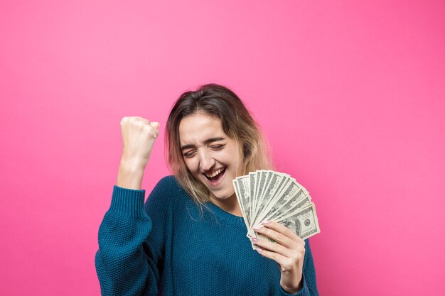 Gros plan de la belle jeune femme dans un pull bleu dans des verres avec de l'argent en dollars américains