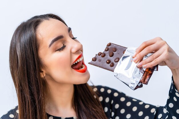 Gros plan d'une belle jeune femme mangeant du chocolat Fond blanc isolé