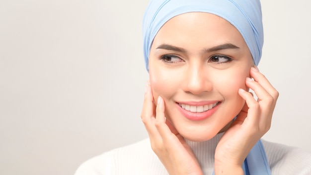 Un gros plan de la belle jeune femme musulmane avec hijab isolé sur fond blanc studio, concept de soins de la peau beauté musulmane.