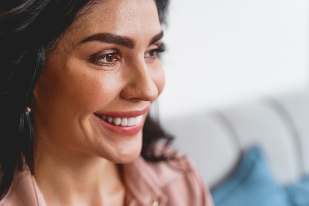 Gros plan de la belle jeune femme regardant loin et souriant.