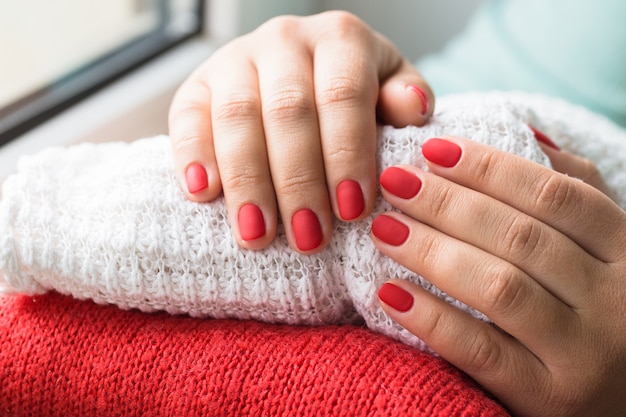 Gros plan d'une belle mains féminines avec des ongles rouges